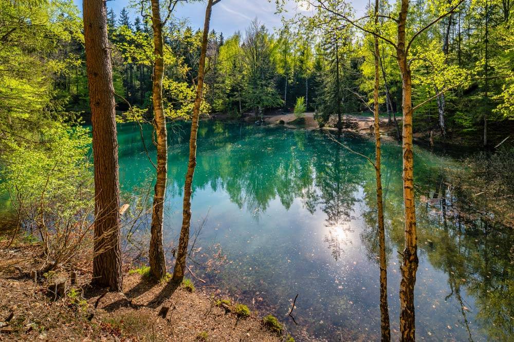 Turkusowa toń Błękitnego Jeziorka otoczona lasem na zboczu Wielkiej Kopy